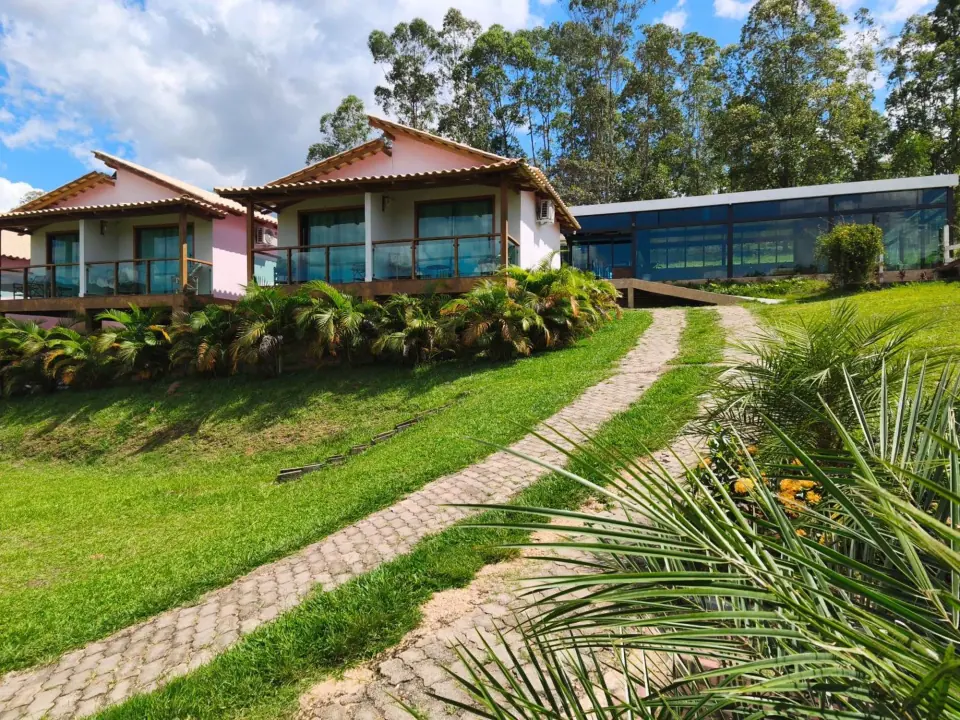 Chalés rosa com varandas de vidro ligados por um caminho curvo no gramado