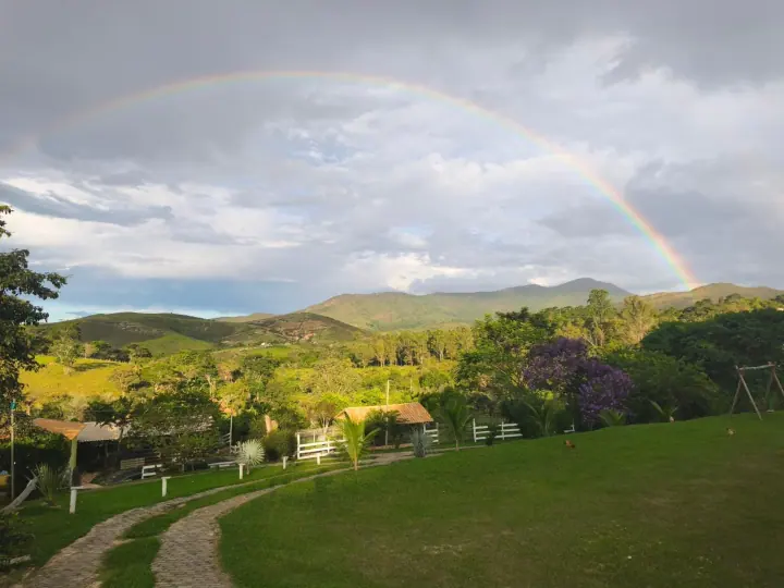 Gramado, caminho e morros sob um arco-íris