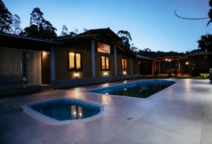 Piscina externa e hidromassagem diante dos edifícios iluminados ao anoitecer